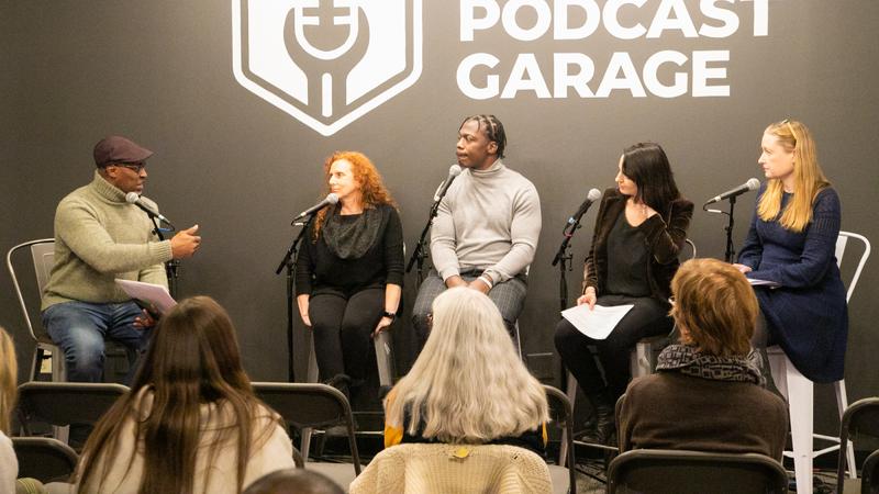 Three white women and two Black men sit on a panel in front of a Podcast Garage logo